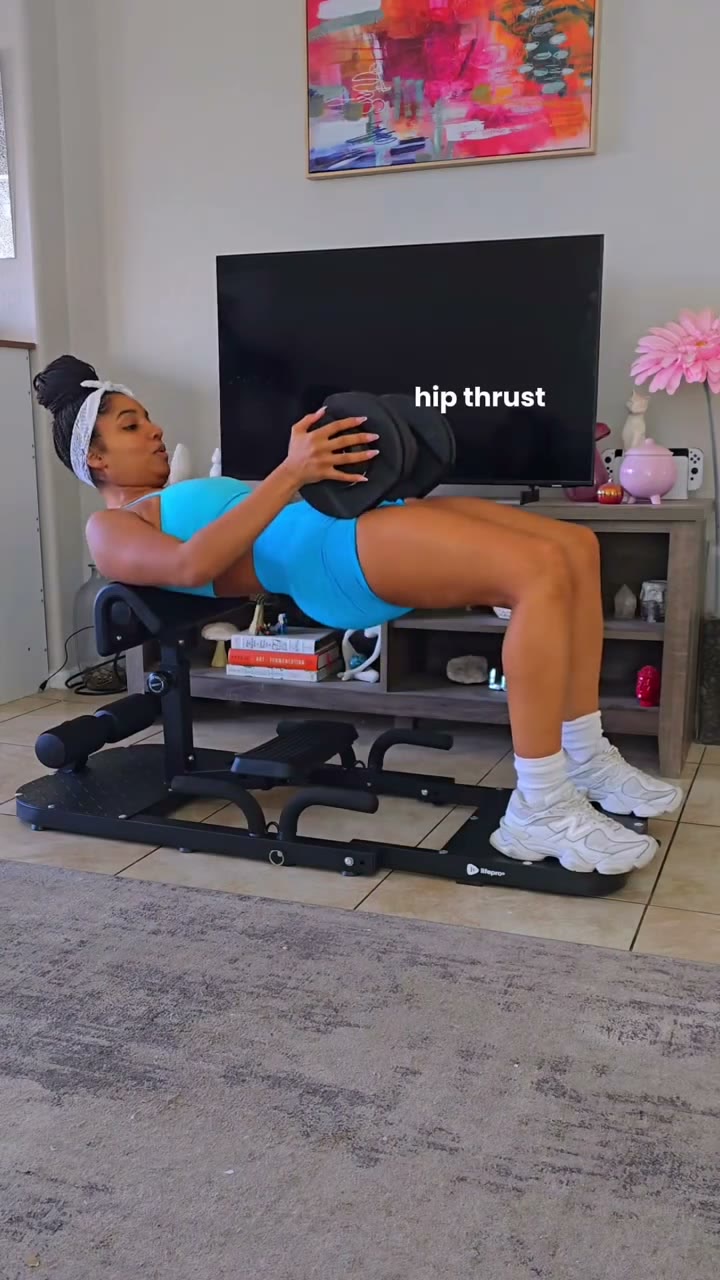 Layla doing a weighted hip thrust on a glute machine in her living room